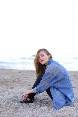 Dinlenme, deniz kenarında oturan ve b kameraya poz güzel kız