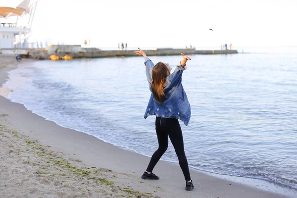 Çekici kız sahil boyunca yürür ve neşeyle kum üzerinde aptallar