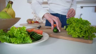 Yakın çekim shot el güzel kadının sebze ışık mutfakta kesme tahtası üzerinde sağlıklı öğle yemeği hazırlar.