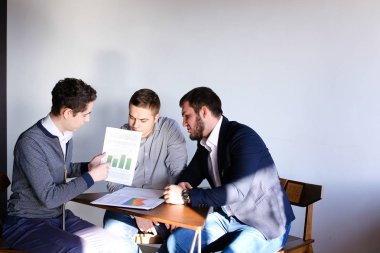 Üç genç erkek programcılar dikkat ederken tablet kullanarak iletişim