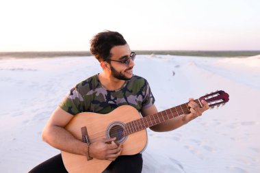 Sevimli genç erkek Arap ses gitar, Hill'de oturan sahiptir