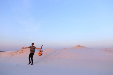 Arap adam çöl güzelliği ile ilham gider ve gitar çi çalış