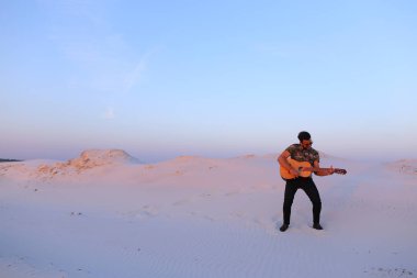 Arap adam çöl güzelliği ile ilham gider ve gitar çi çalış