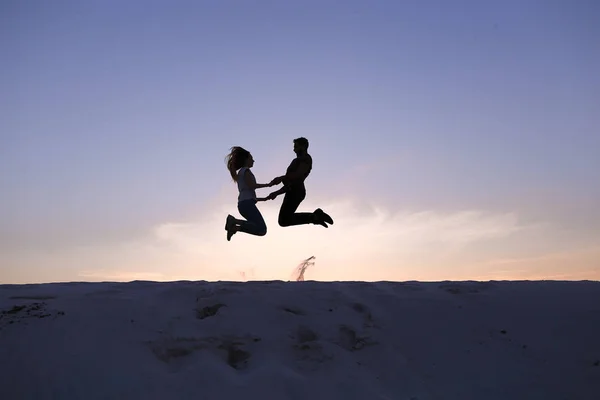 Веселый парень и девушка веселятся и танцуют на вершине песчаной дюны — стоковое фото