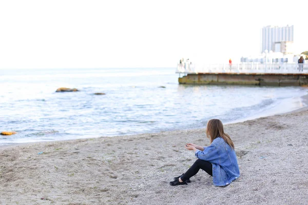 年轻漂亮的女人放松坐在沙滩上，享受视图 o — 图库照片