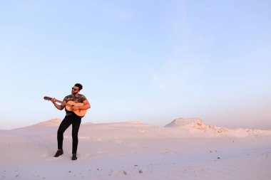 Arap adam çöl güzelliği ile ilham gider ve gitar çi çalış