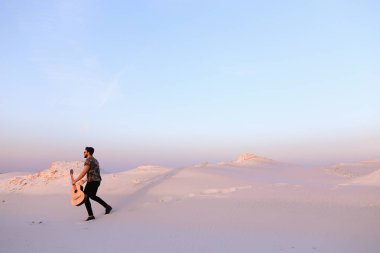 Arap adam çöl güzelliği ile ilham gider ve gitar çi çalış