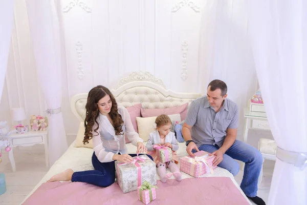 Vriendelijke familie in feestelijke stemming voor het uitwisselen van geschenken zittend op bed — Stockfoto