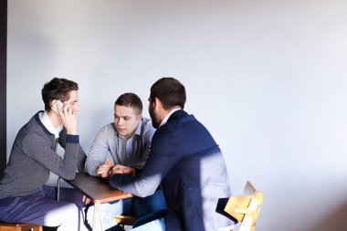 Üç genç erkek programcılar dikkat ederken tablet kullanarak iletişim