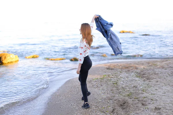 Очаровательная девушка идет вдоль берега и веселые дураки вокруг на песке — стоковое фото