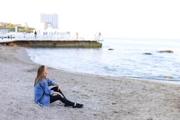 Mulher bonita relaxa sentado na praia e goza de vista o — Fotografia de Stock