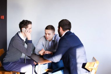 Üç genç erkek programcılar dikkat ederken tablet kullanarak iletişim