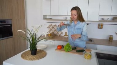 Sevimli kadın elinde telefon aşçılar ve kompozisyon için fotoğraf, şık mutfak ortasında gündüz ayakta sebze oluşturur.