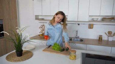 Hoş dişi hücre ve salata sebze, öğleden sonra şık mutfak ortasında hazırlamak olacak sohbet eden.