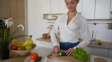 Sevimli kız dilim salatalık kesme tahtası modern mutfak bıçağı ile.
