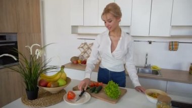 Güzel kız modern mutfak kesme tahtası üzerinde taze sebze salatası hazırlama.