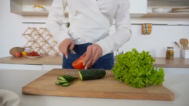 Ama de casa hembra corta tomate con cuchillo en la tabla de cortar en la cocina moderna . — Vídeos de Stock