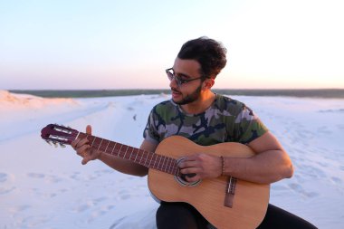 Sevimli genç erkek Arap ses gitar, Hill'de oturan sahiptir