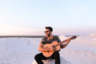 Çekici Arap adam gitar, Hill'de oturan şarkı söylüyor