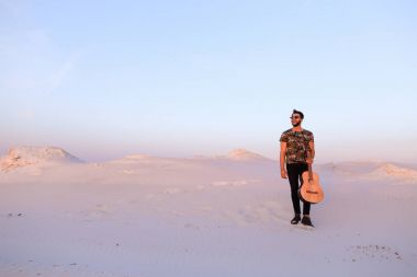 Dese aracılığıyla elinde gitar ile görkemli Müslüman genç adam yürüyor