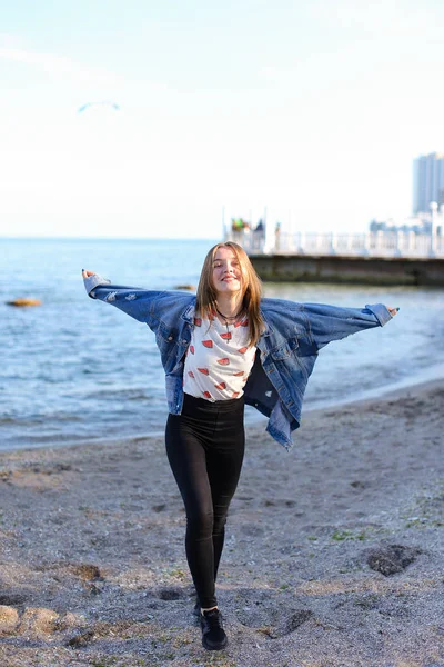 Heureuse jeune femme aime le temps ensoleillé et posant sur le rivage de bl — Photo