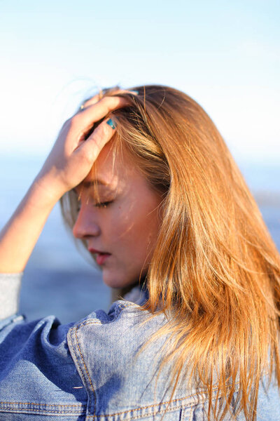 Pretty girl with back to camera enjoying sea air, stands on seas