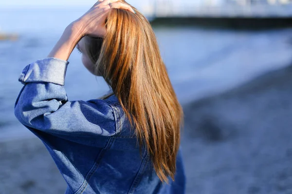 Csinos lány turista, aki a tengerparton áll, és fejleszti a haj, hu — Stock Fotó