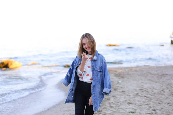 Charming woman with smile poses and walks along sea shore on war — Stock Photo, Image