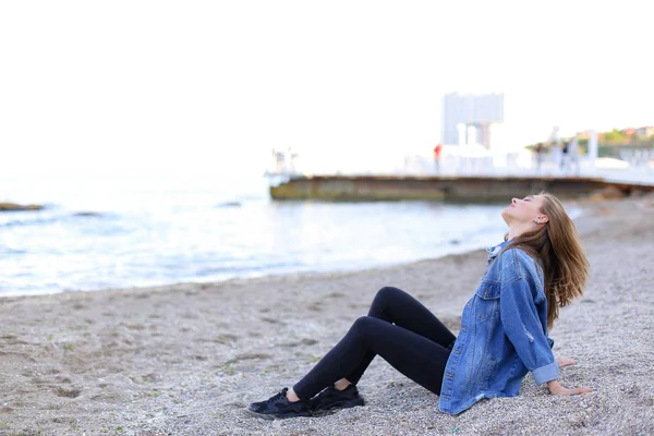 Sorrindo jovem descansa na praia e posa na câmera, sentado — Fotografia de Stock