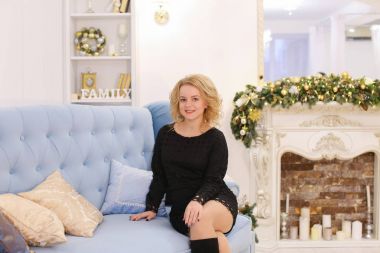 Gülümseyen ve kanepede oturan poz muhteşem genç sarışın kadın