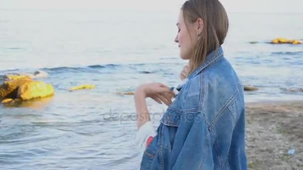 Movimento lento Mulher bonita sorri facilmente e olha para o horizonte, de pé na costa da onda do mar na noite de verão fresco . — Vídeo de Stock