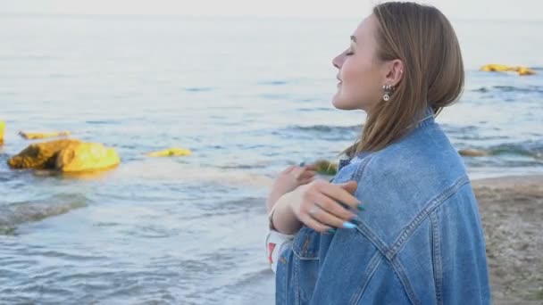 Slow Motion Retrato de mulher bonito que respira ar fresco do mar e posa com sorriso, ficar contra o mar azul e céu à noite . — Vídeo de Stock