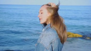 Güzel kız teşkil etmektedir ve kamera, sıcak yaz akşamı deniz arka plan üzerinde duran gülümsüyor ağır çekim portre.