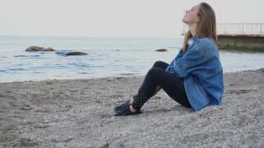 Ağır çekim çekici kız tatil deniz şehir ve deniz ve gökyüzü fon karşı yarı uykuda üzerinde plaj sahiptir sıcak yaz akşamı