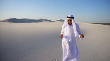 Aktif genç erkek Emirliği Arap BAE Şeyh hayatta sevinir ve açık akşamı çölün expanses yürüyor.