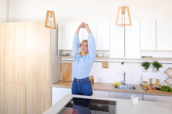 Pretty girl walks into kitchen and stretches, enjoying morning c