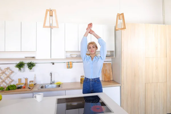 Pretty girl walks into kitchen and stretches, enjoying morning c