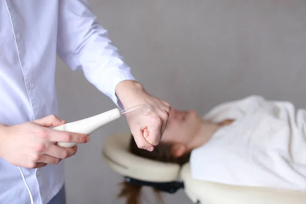 Male expert cosmetician demonstrates work of massage device for — Stock Photo, Image