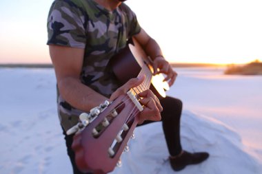 Arap yakışıklı arasında kum tepe üzerinde duran gitar çalmak