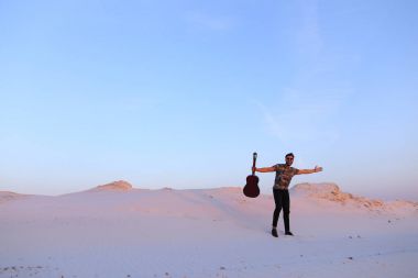 Arap adam çöl güzelliği ile ilham gider ve gitar çi çalış