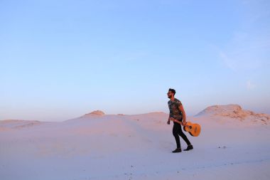 Dese aracılığıyla elinde gitar ile görkemli Müslüman genç adam yürüyor