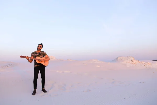 Gutaussehender arabischer Mann, der mitten auf dem Boden stehend Gitarre spielt — Stockfoto