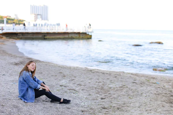 Όμορφη νεαρή γυναίκα χαλαρώνει κάθεται στην παραλία και απολαμβάνει θέα o — Φωτογραφία Αρχείου