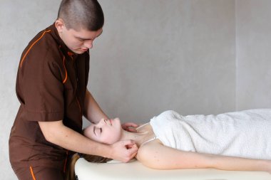 Adam masör güçlü elleriyle yalan genç kız, boyun kneads