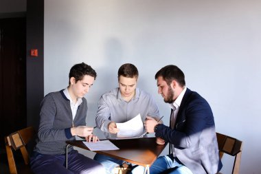 Üç genç erkek programcılar dikkat ederken tablet kullanarak iletişim