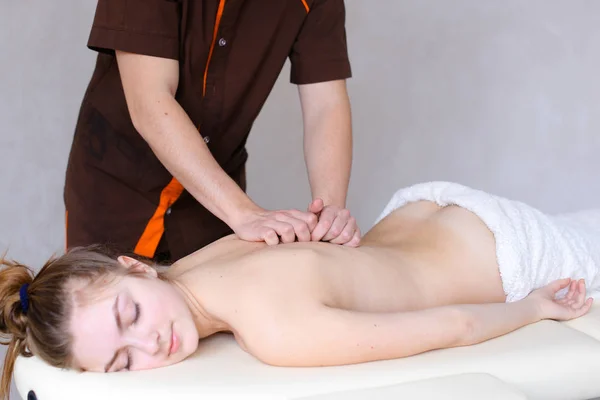 Profesjonalnego masażysty mężczyzna ugniata dziewczyny do pacjenta, którzy leżą — Zdjęcie stockowe