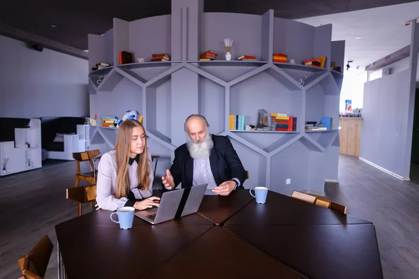 Businesswoman using laptop with old man colleague in successful