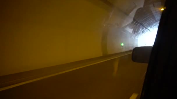 Samochód opuszcza tunel i jeździ w pobliżu pól. — Wideo stockowe