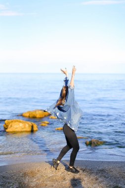 Çekici kız sahil boyunca yürür ve neşeyle kum üzerinde aptallar