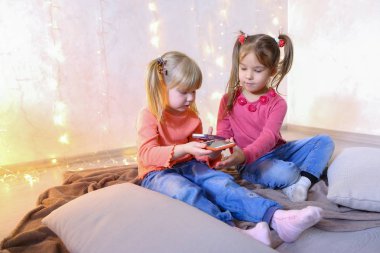 Mutlu küçük kızlar akıllı telefonlar eğlence için kullanın ve oturmak